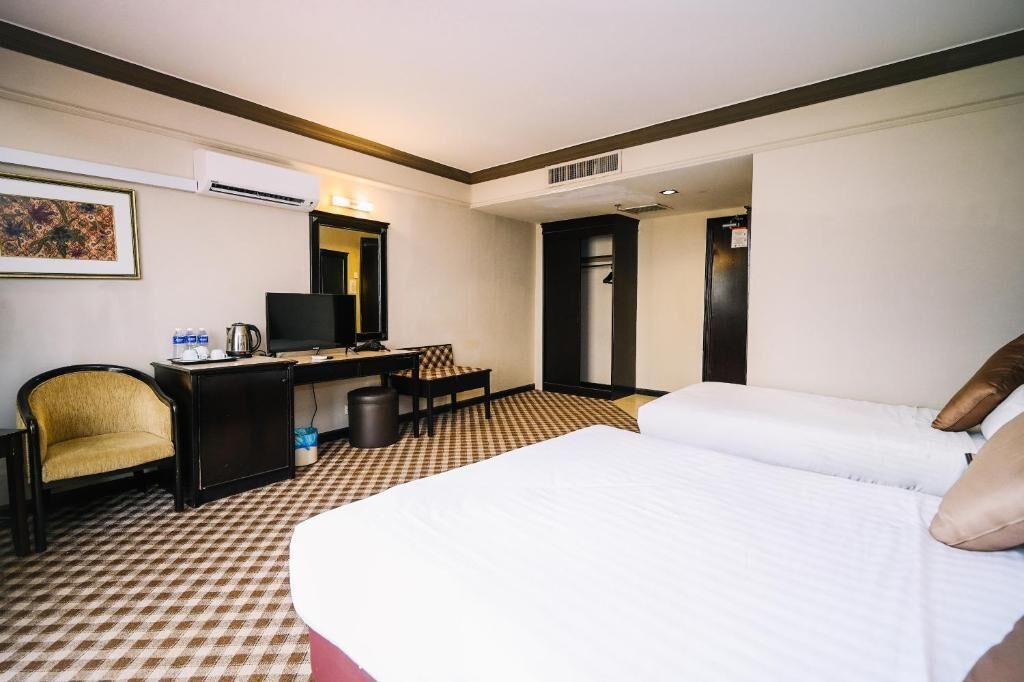 Habitació d'hotel amb un llit, escriptori, cadira, televisió i aire condicionat.