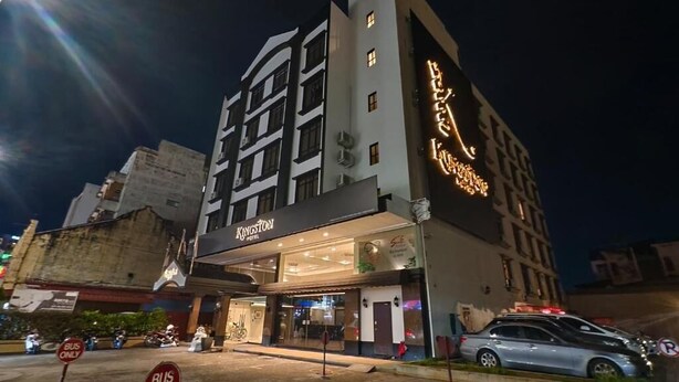 Un hotel con fachada moderna, un letrero llamativo y un estacionamiento.