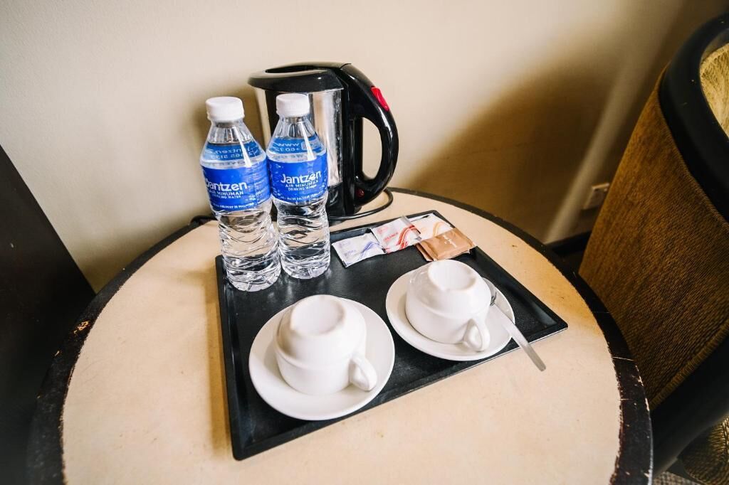 Une petite table avec deux tasses blanches, deux bouteilles d’eau, une cafetière noire et un plateau.