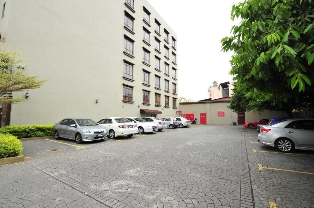 A parking lot with several cars parked in front of a building with multiple windows and a red door.