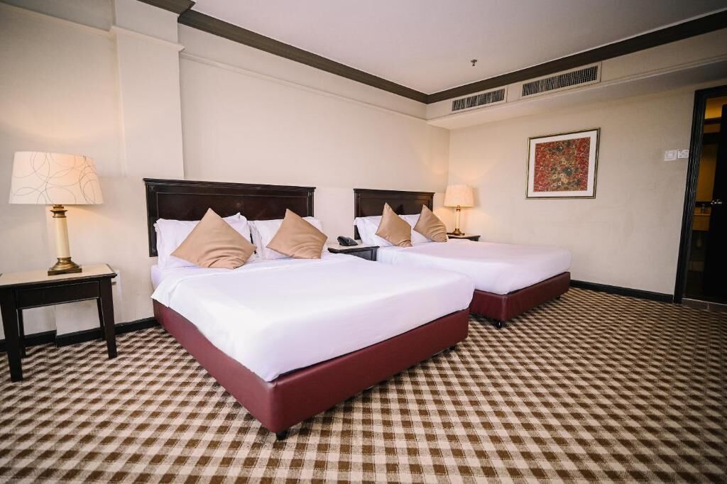 A hotel room with two beds, checkered carpet, and a painting on the wall.