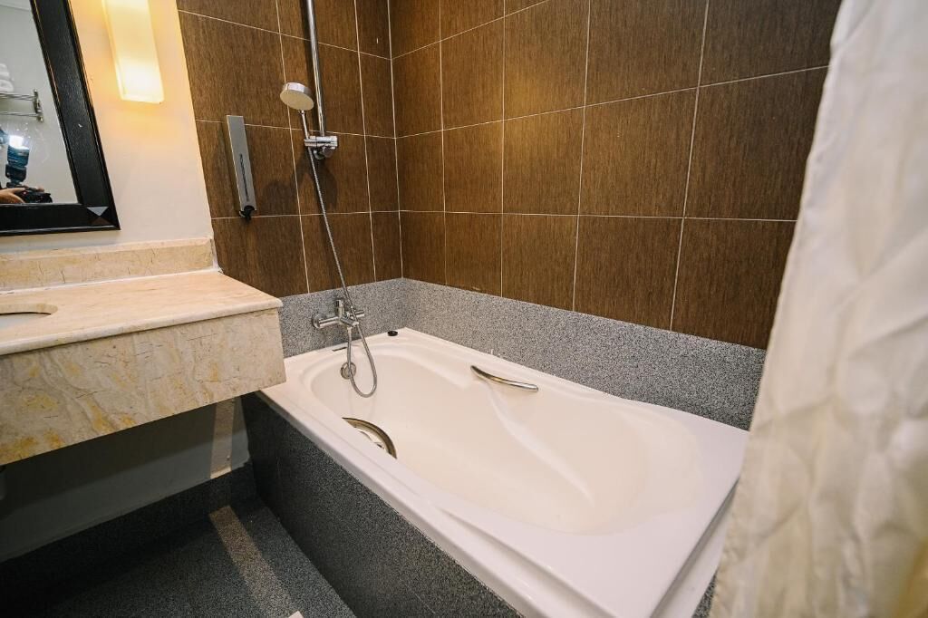 A bathroom with a bathtub, a shower, and a vanity with a mirror.