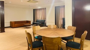Una habitación de hotel con una mesa de comedor redonda de madera, rodeada por seis sillas, un sofá y una mesita de centro.