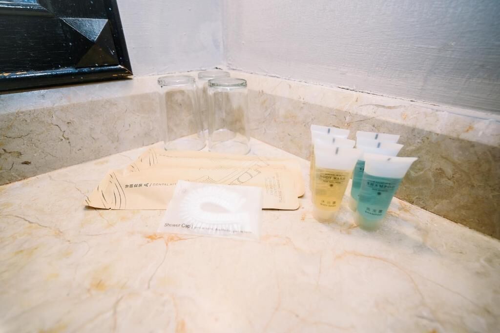 Uma bancada de banheiro com produtos de higiene pessoal e touca de banho.