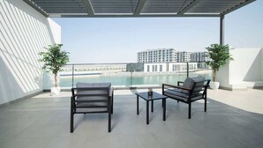 A balcony with two chairs and a table, overlooking a body of water and buildings. - Beachfront Villa W Private Pool & Sea Views (Ajmal Makan)
