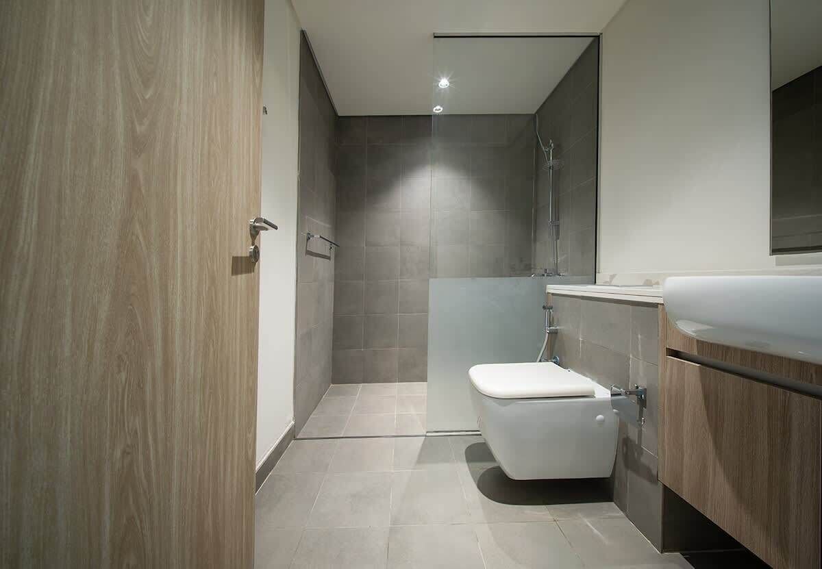 Een moderne badkamer met douche, toilet en wastafel.