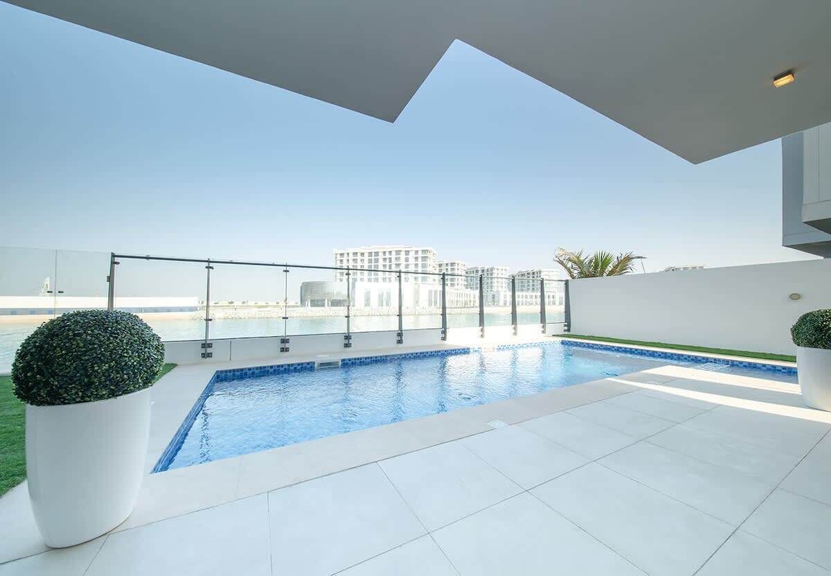 A modern outdoor swimming pool with a clear view of the city skyline in the background.