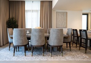 A dining area with a round table, six chairs, and a patterned rug.