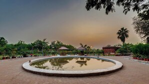 A circular water feature surrounded by a paved walkway, with potted plants and a gazebo in the background. - Royal Safari Lakeside Resort- Little Rann of Kutch (Dasada)