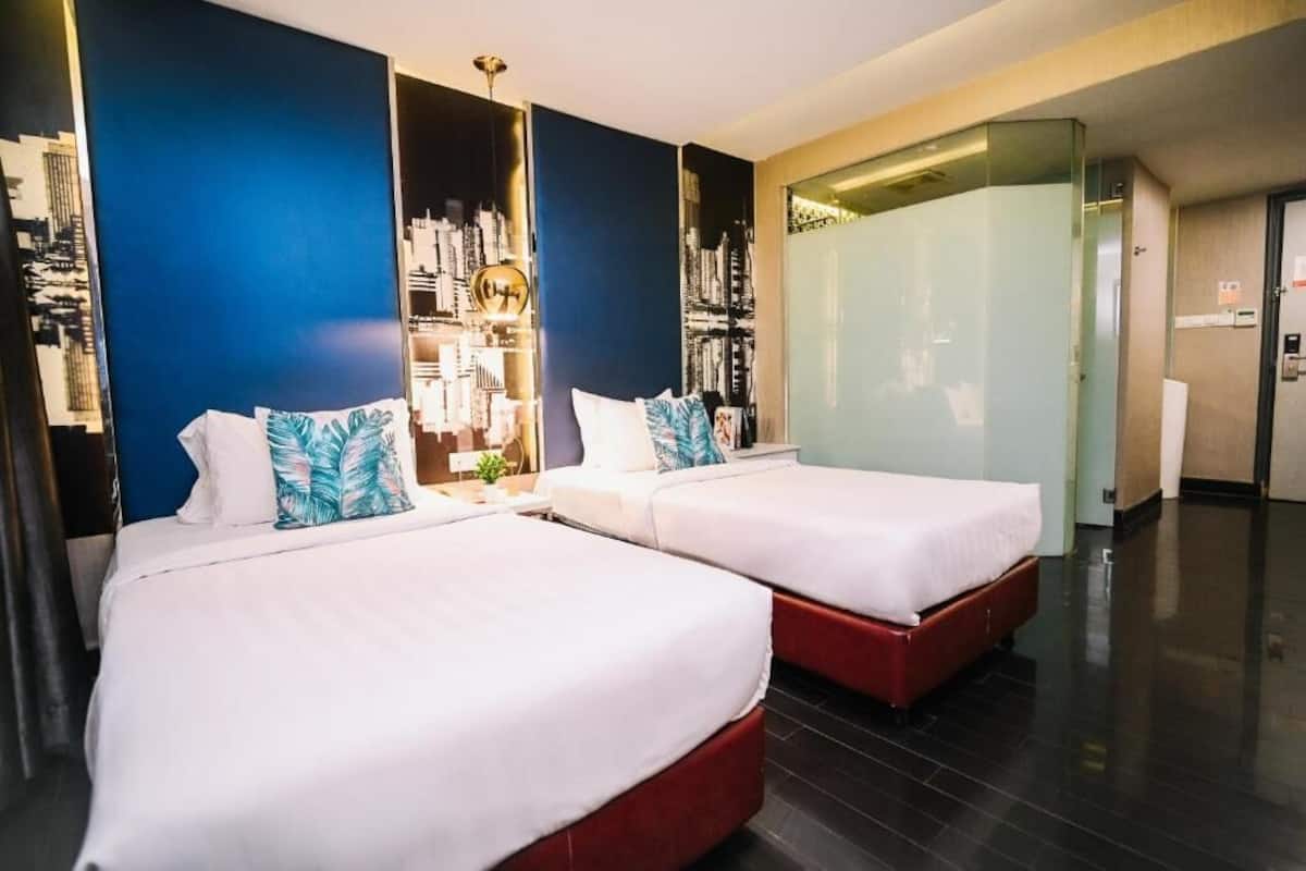 Habitación de hotel con dos camas, un mural de paisaje urbano y un separador de vidrio.