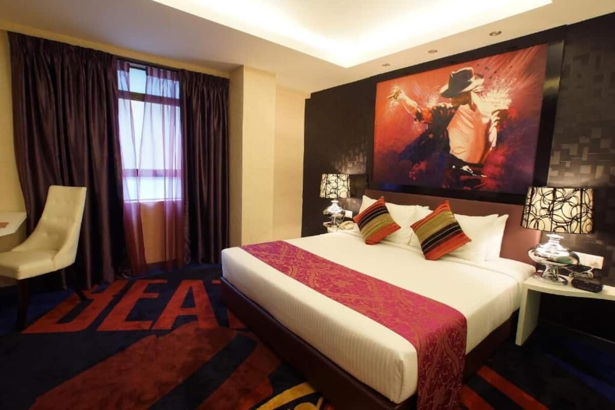 Habitación de hotel con una cama grande, una silla, un televisor y un cuadro en la pared.