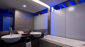 Une salle de bain moderne avec deux lavabos, une baignoire et un grand miroir.