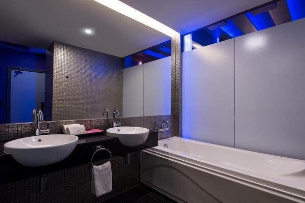 Une salle de bain moderne avec deux lavabos, une baignoire et un grand miroir.
