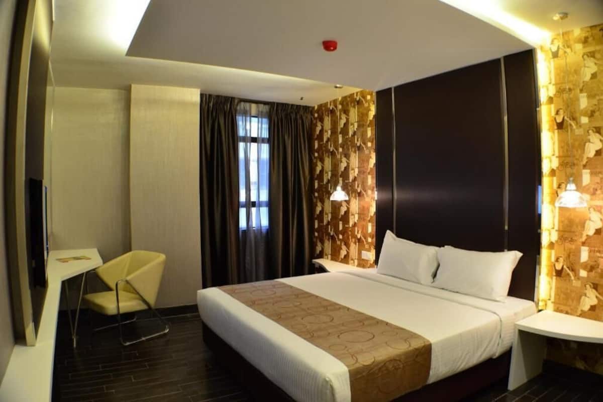 Una habitación de hotel con una cama, una silla, un escritorio y una pared con diseño decorativo.