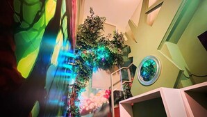 Un intérieur moderne avec un escalier, un luminaire circulaire fixé au mur et un mur végétal.
