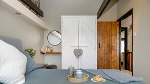 Une chambre à coucher avec un lit, une armoire, un miroir et une petite table sur laquelle se trouvent une tasse et une assiette de biscuits.