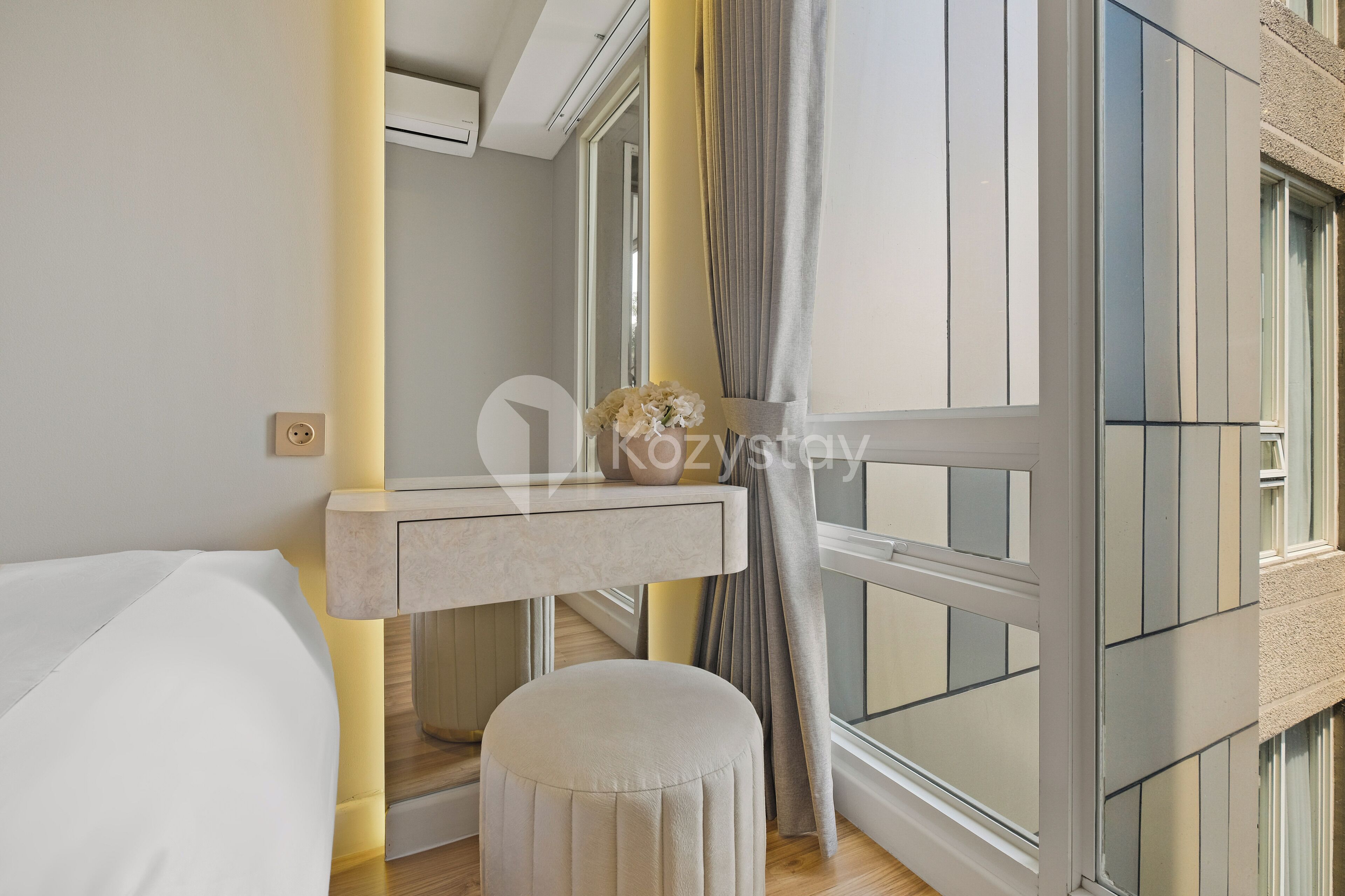 A modern bedroom with a bed, bedside table, and a small stool.
