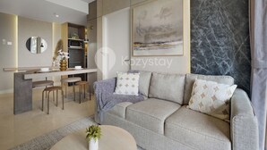 Ein modernes Wohnzimmer mit einer Couch, einem Couchtisch und einer Küchenzeile im Hintergrund.
