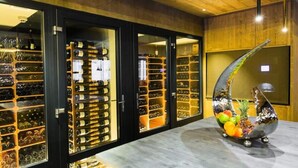 Une cave à vin dotée de plusieurs étagères remplies de bouteilles, d’un sol en marbre et d’une sculpture d’oiseau décorative.