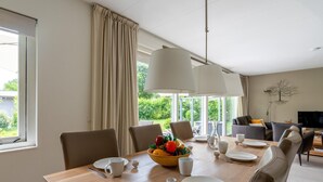 A dining area with a wooden table set for four, a bowl of fruit, and a view of the outdoors. - Tastefully Furnished Country House for 6 People (Den Burg)