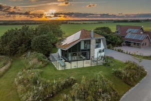 Uma casa moderna com fachada de vidro generosa, um pátio espaçoso e painéis solares no telhado.