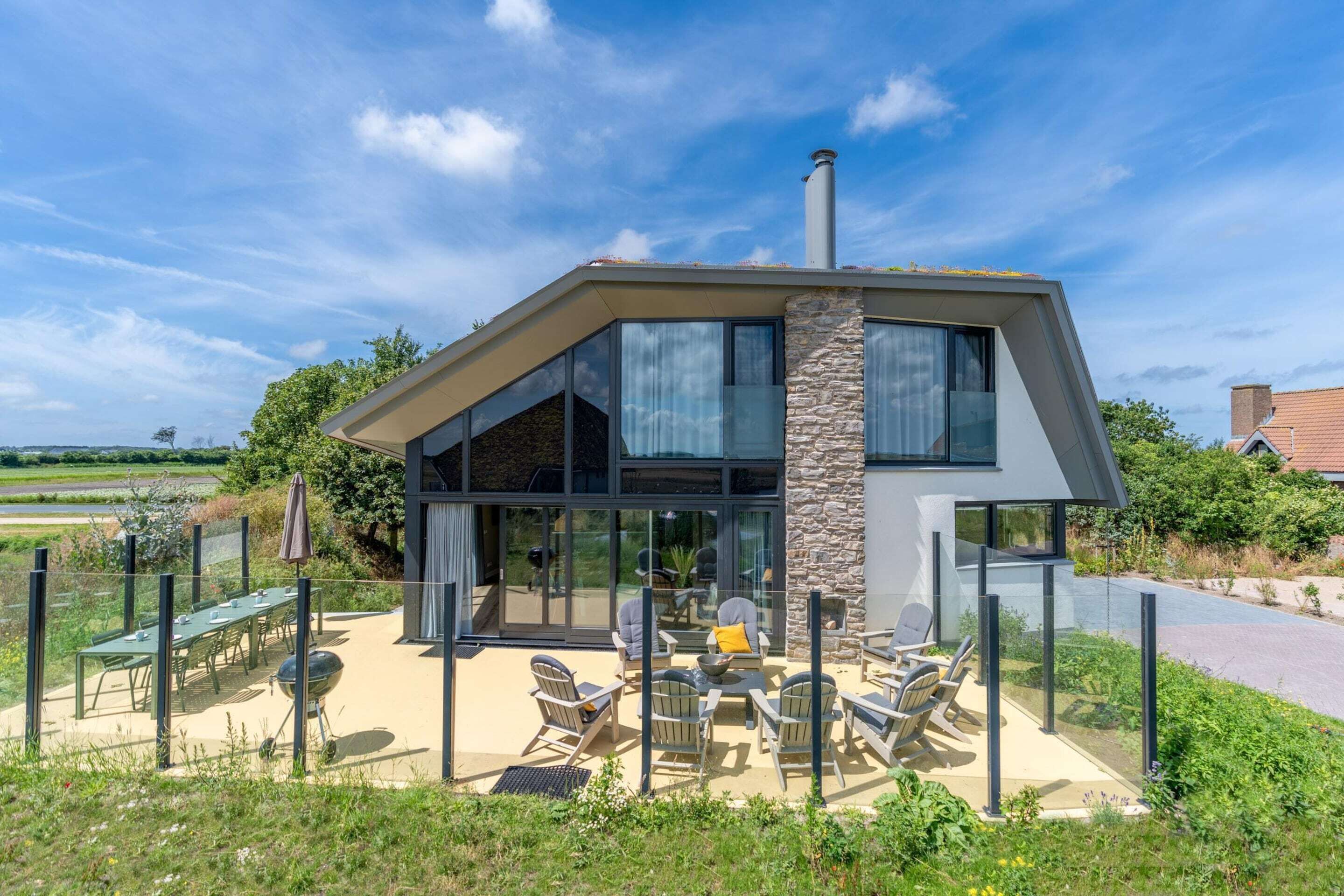 A modern house with a patio, outdoor seating, and a chimney.