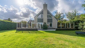 Een modern huis met een groot gazon, een overdekte patio en een schoorsteen.