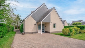 Een gelijkvloers gebouwd huis van baksteen met een schuin dak en een verharde oprit.