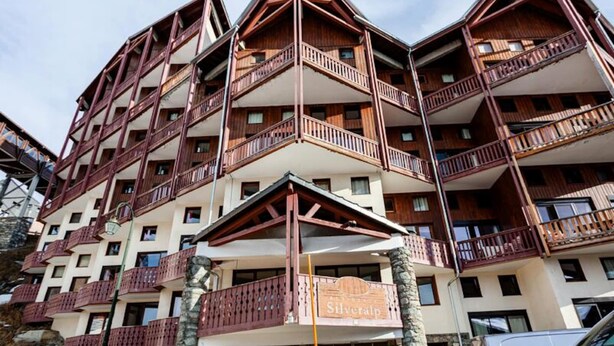 A multi-story hotel with balconies, a ski lift in the background, and a sign for 'Silverp'. - Apartment in Silveralp Near Ski Slopes (Les Belleville)
