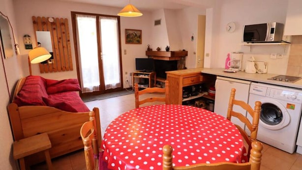 A cozy living room with a wooden sofa, a red polka dot table, and a washing machine in the corner. - Apartment in Areches Beaufort Ski Access (Beaufort)