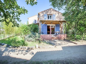 A house with a covered porch, a garden with various plants, and a clear sky. - Holiday Home 150m From the Beach in Corsica (Poggio-Mezzana)