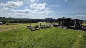 A modern house with a garden, outdoor seating, and a view of the countryside. - Spacious Valley Views Near City & Coast (Whareora)