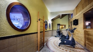 A gym with exercise equipment, a wooden ladder, and a circular window with a snowy scene. - Apartment in Savoy Near Ski Slopes (Bourg-Saint-Maurice)