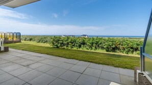 Een ruim balkon met een helder uitzicht over een weelderig groen landschap en gebouwen in de verte.