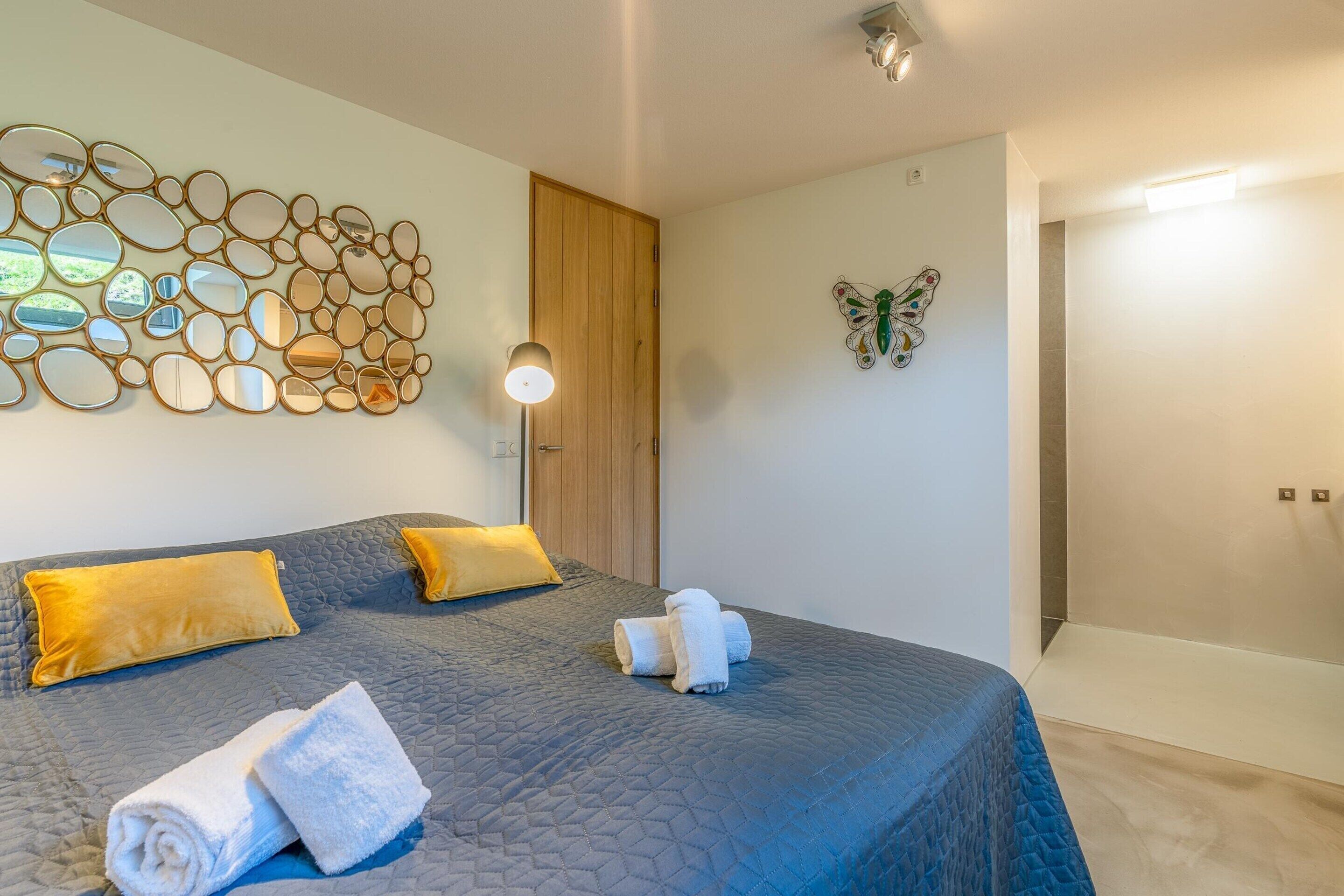 Een slaapkamer met een groot bed, twee kussens, een kunstwerk aan de muur en een deur.