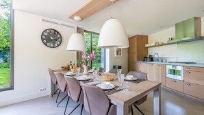 Une cuisine moderne avec un coin repas, des poutres apparentes en bois au plafond et une grande fenêtre.