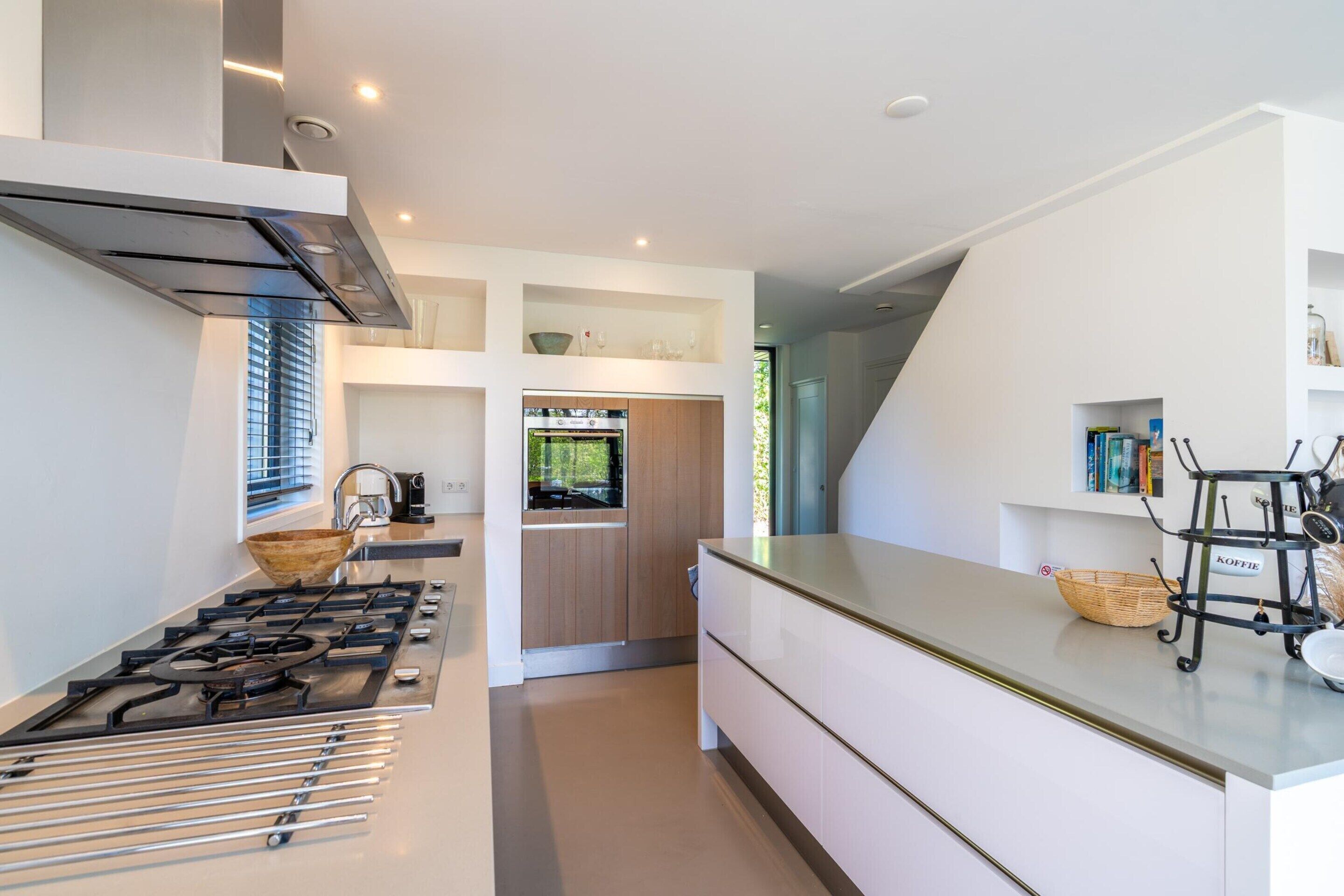 A modern kitchen with a gas stove, wooden cabinets, and a built-in oven.