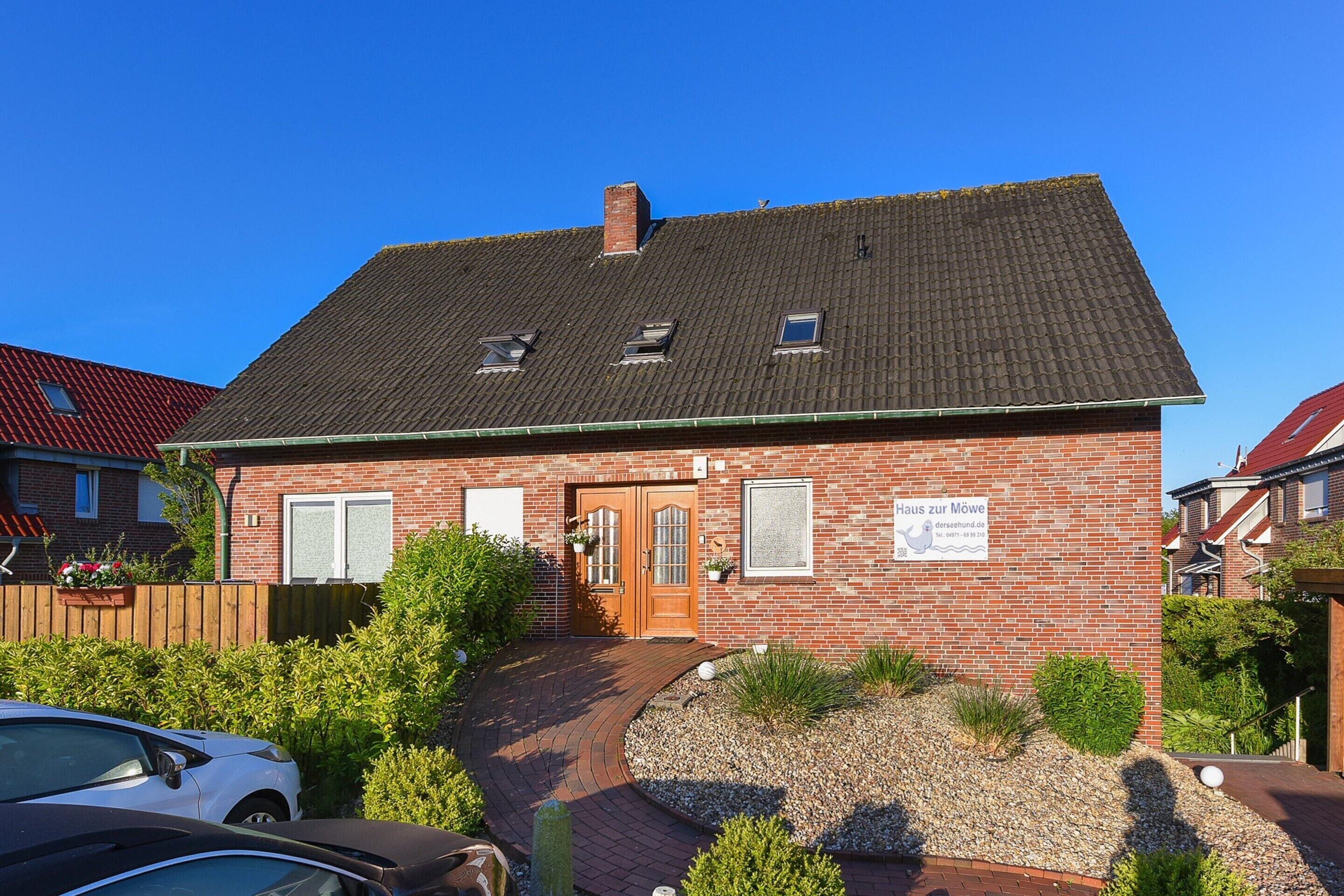 A two-story brick house with a sloped roof, a front door, and a small window.