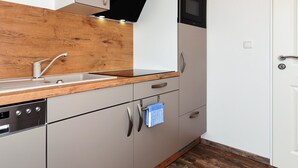 Een moderne keuken met een houten aanrechtblad, een ingebouwde magnetron en een vaatwasser.