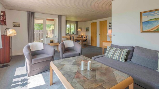 A cozy living room with a sofa, two armchairs, a coffee table with candles, and a painting on the wall. - 5 Star Holiday Home in Haarby (Haarby)