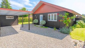 A modern house with a red roof, a covered porch, and a gravel driveway. - 5 Star Holiday Home in Haarby (Haarby)
