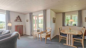A cozy room with a wooden ceiling, a dining table with chairs, a sofa, and a small cabinet. - 5 Star Holiday Home in Haarby (Haarby)
