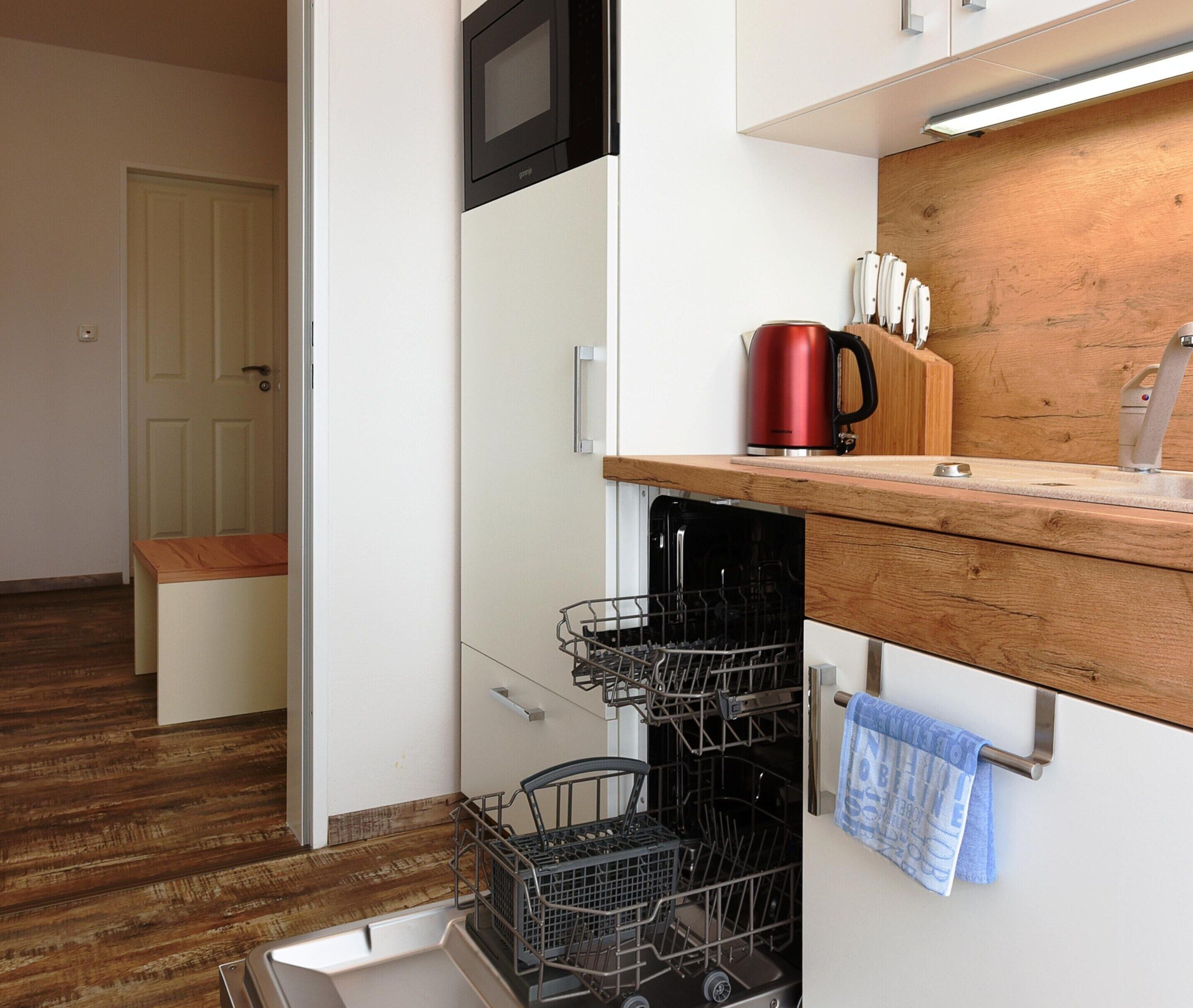 A kitchen with a microwave, a red kettle, and a dish rack.