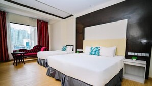 A hotel room with two beds, a red armchair, a small table, and a city view. - Kingston Hotel 5 at Chow Kit (Kuala Lumpur)