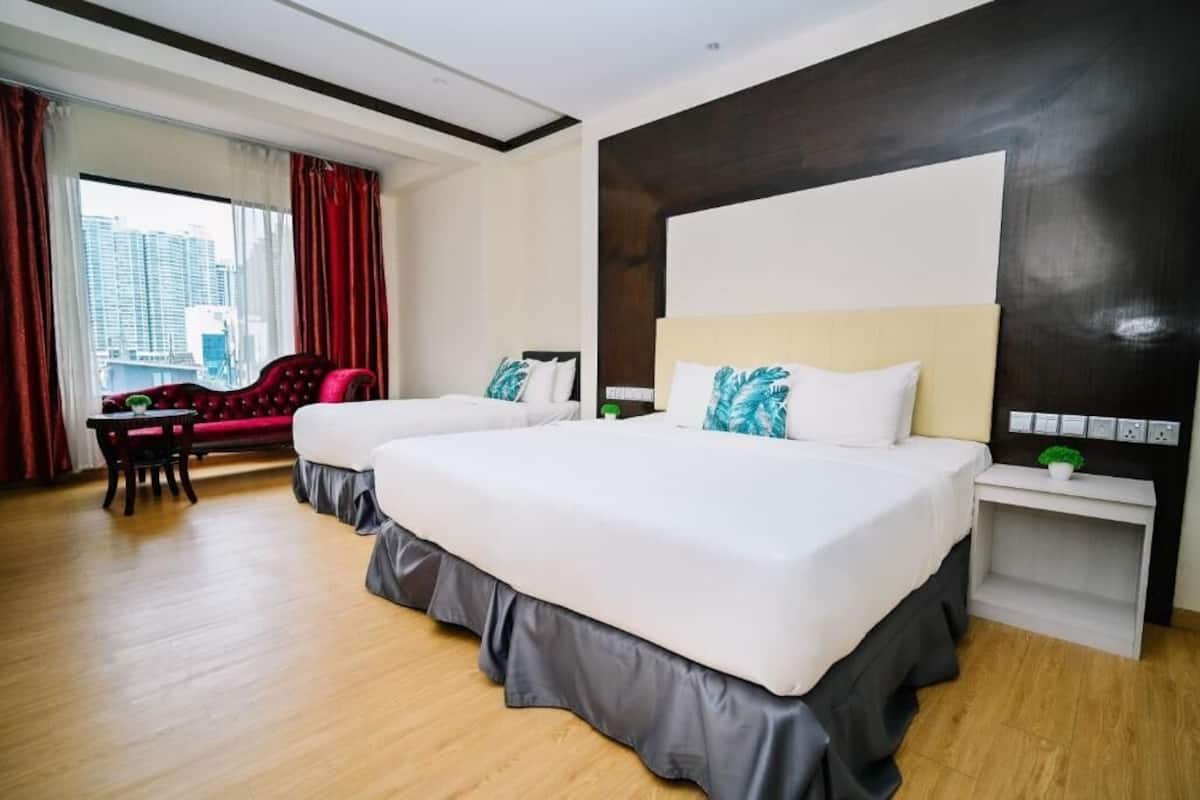 A hotel room with two beds, a red armchair, a small table, and a city view.