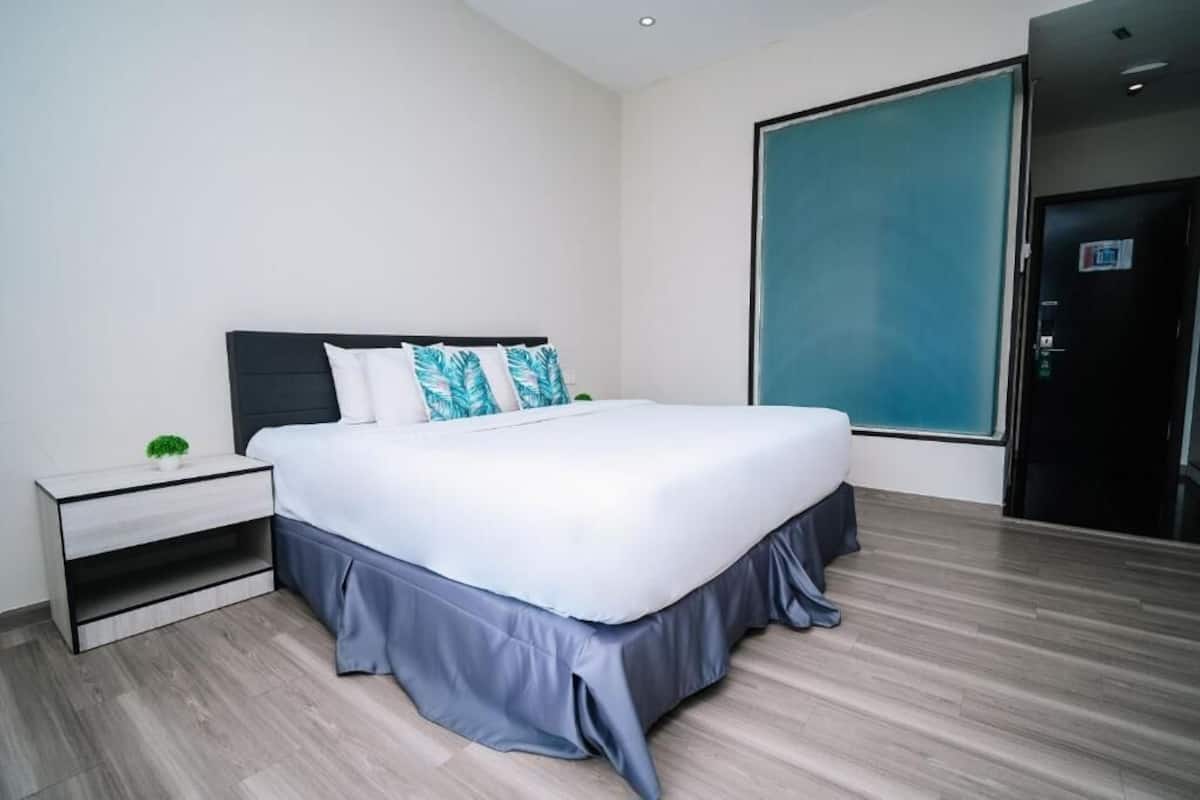 A modern hotel room with a large bed, a nightstand, and a view of the outside.