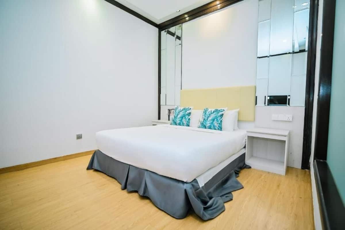 A modern bedroom with a large bed, a bedside table, and a mirror.