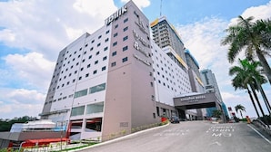 Un hotel moderno con un llamativo letrero de 'Abilrik', una entrada del 'Kingston Hotel Premier' y un cielo despejado.