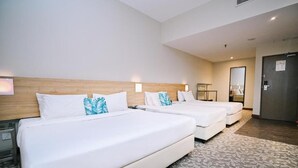 Una habitación de hotel con dos camas, un cabecero de madera, un espejo y una puerta.