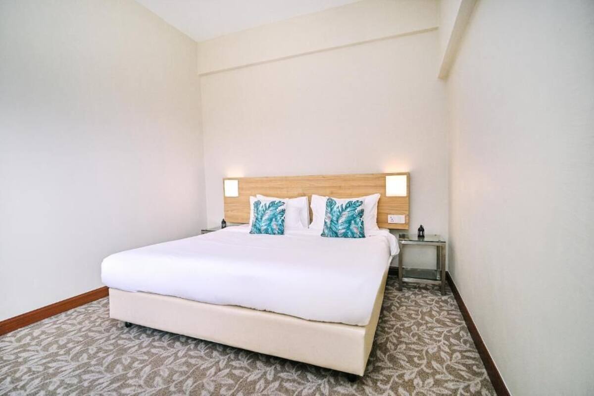 Une chambre d’hôtel avec un grand lit, deux tables de chevet et une petite table.